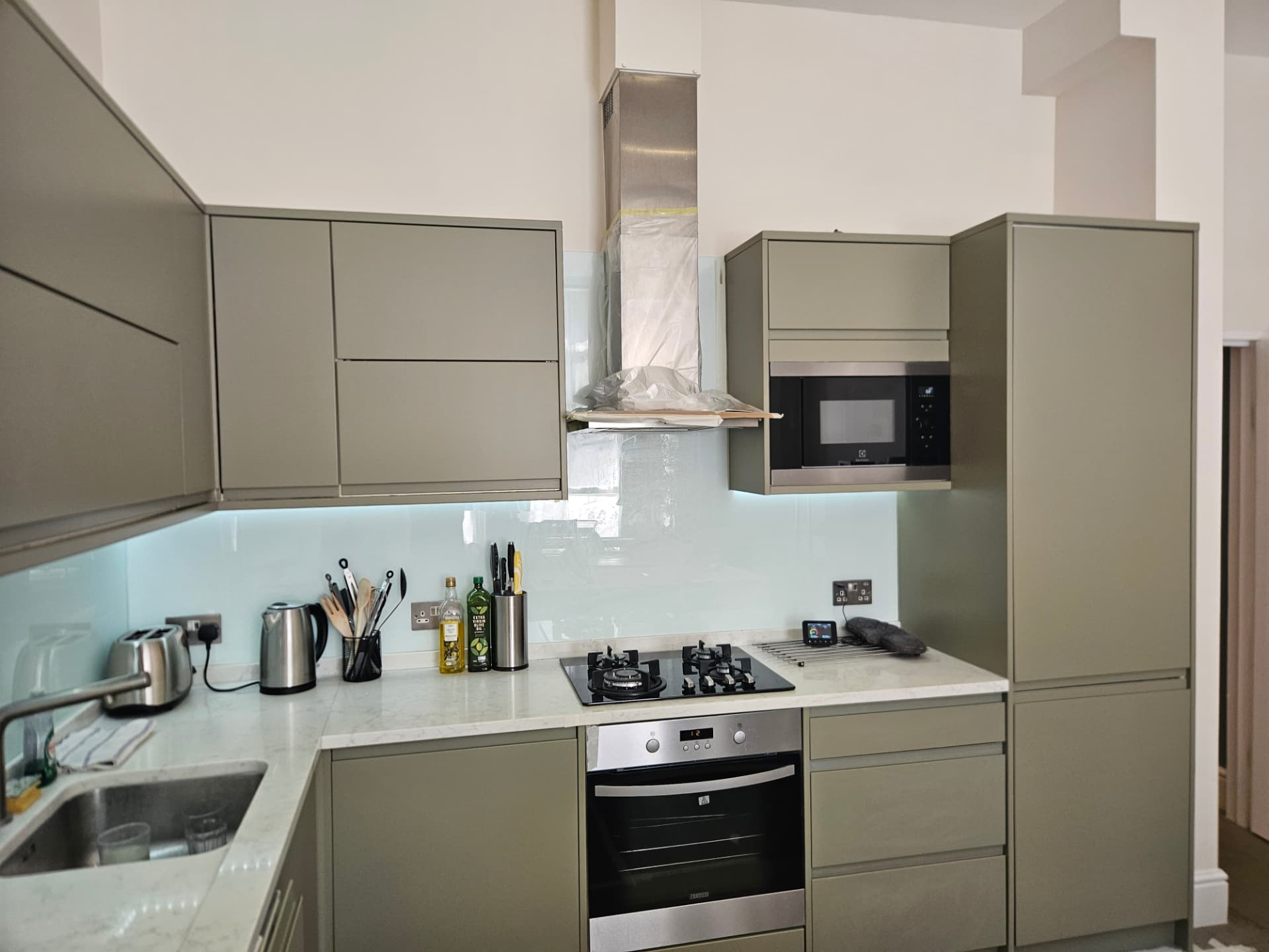 After — Maida Vale kitchen transformation in farrow & ball treron. Finished run of cabinets, oven and tall storage in low-sheen matt.