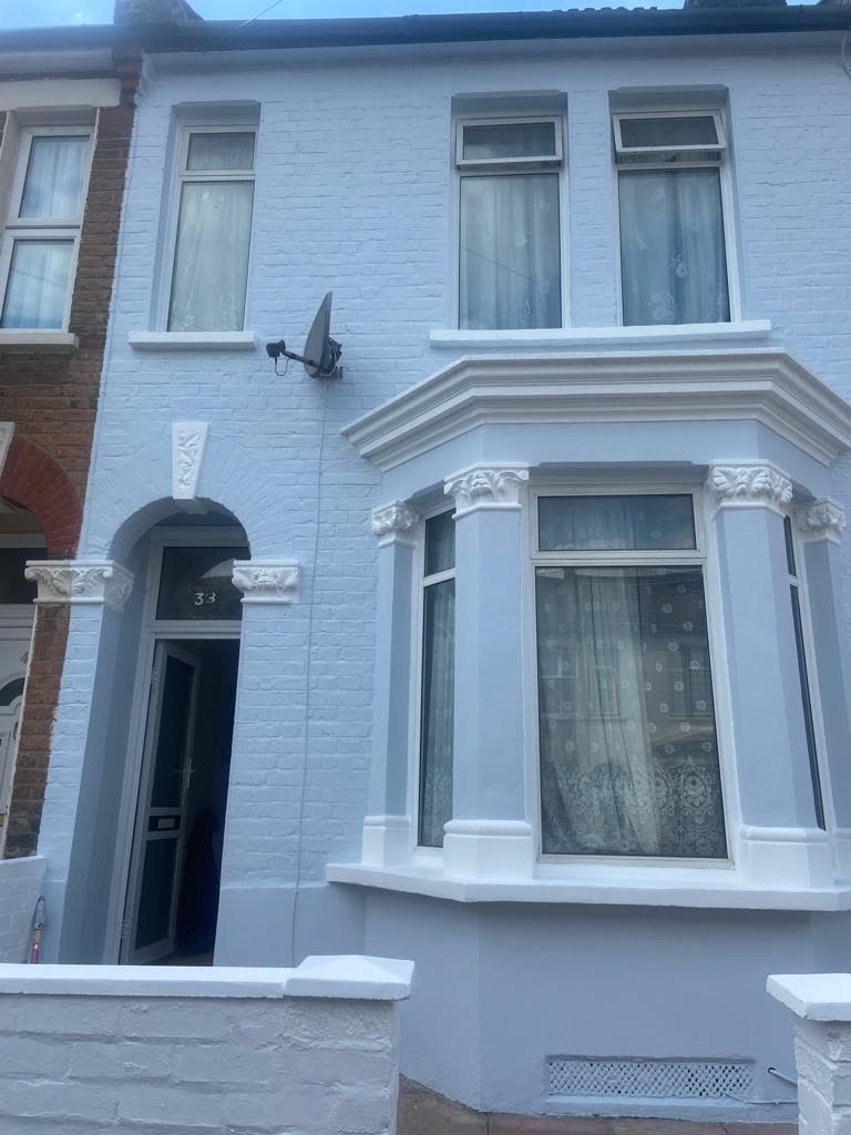After photo — Charlton victorian terrace exterior in light blue. Painted brickwork in soft light blue with the bay window, corbels and sills picked out in white.