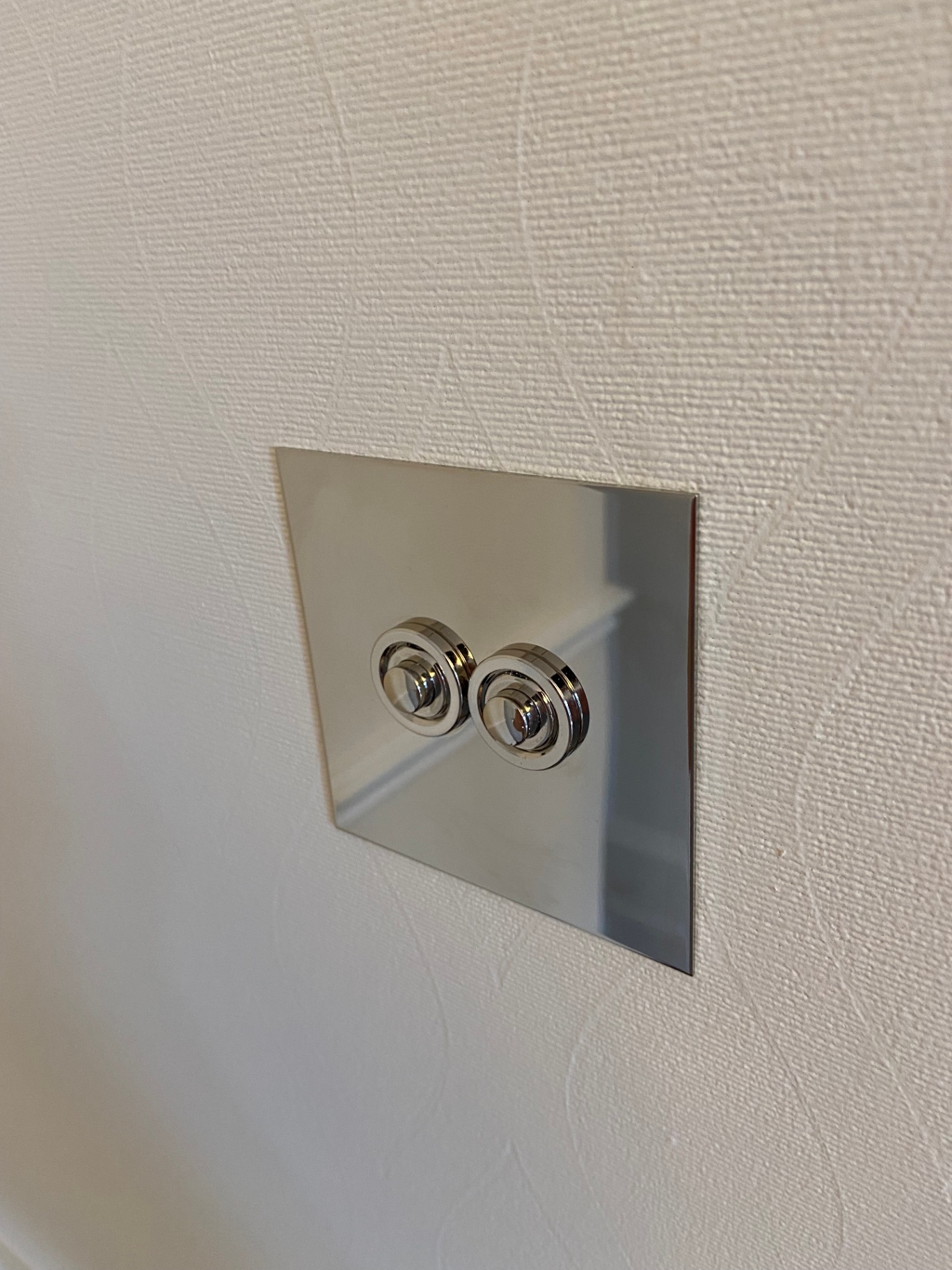 Crisp Farrow & Ball Tallow 203 paintwork cut around a polished chrome rocker switch — Belgravia decorating detail