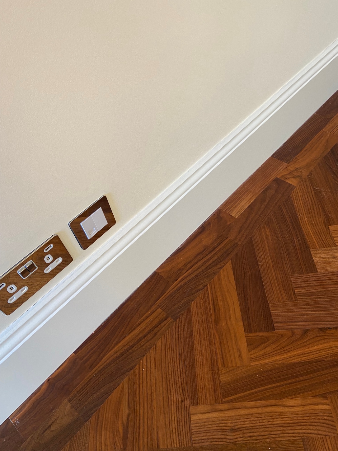 Hand-brushed eggshell white skirting line meeting parquet flooring beneath Farrow & Ball Tallow 203 wall — Belgravia SW1