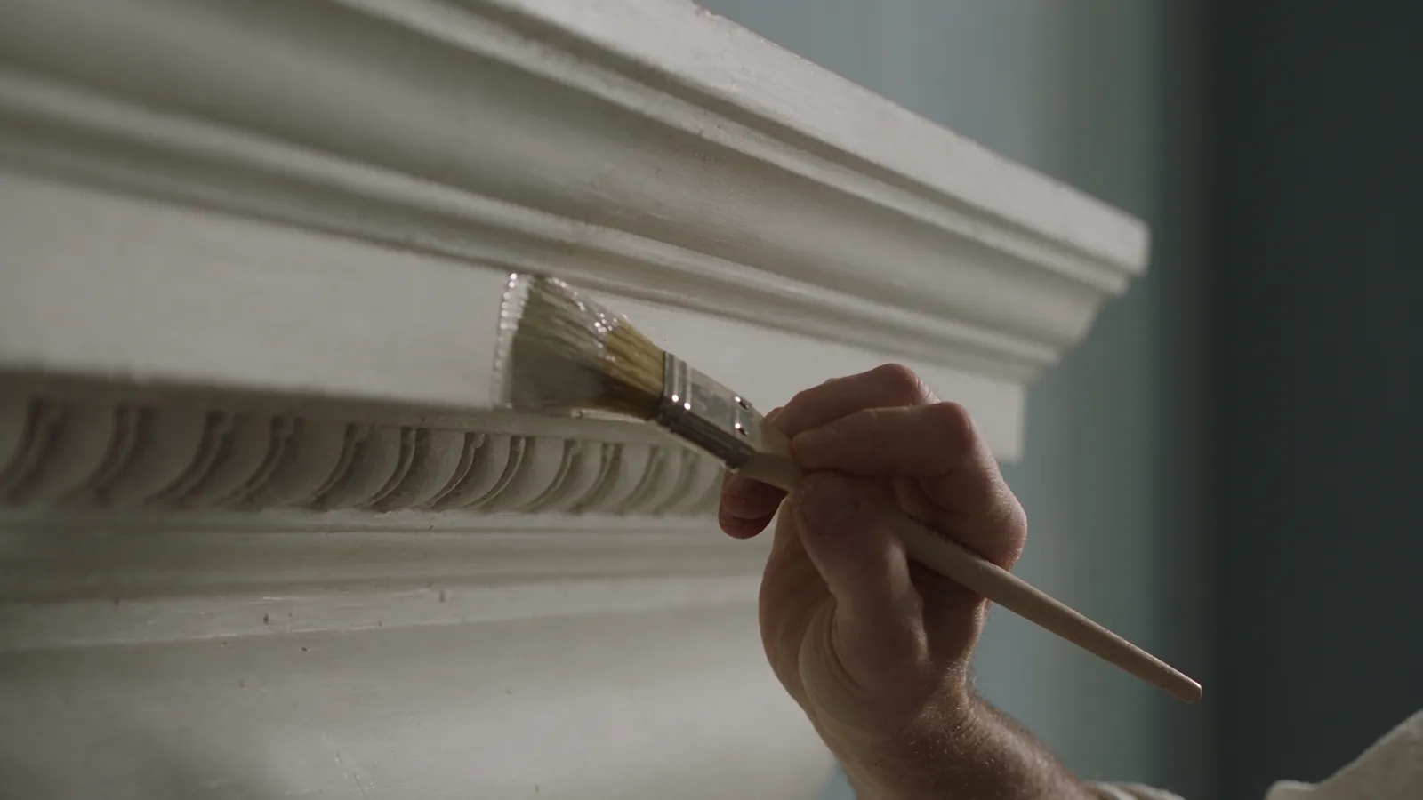 Decorator hand-painting ornate plaster detail in a London period home
